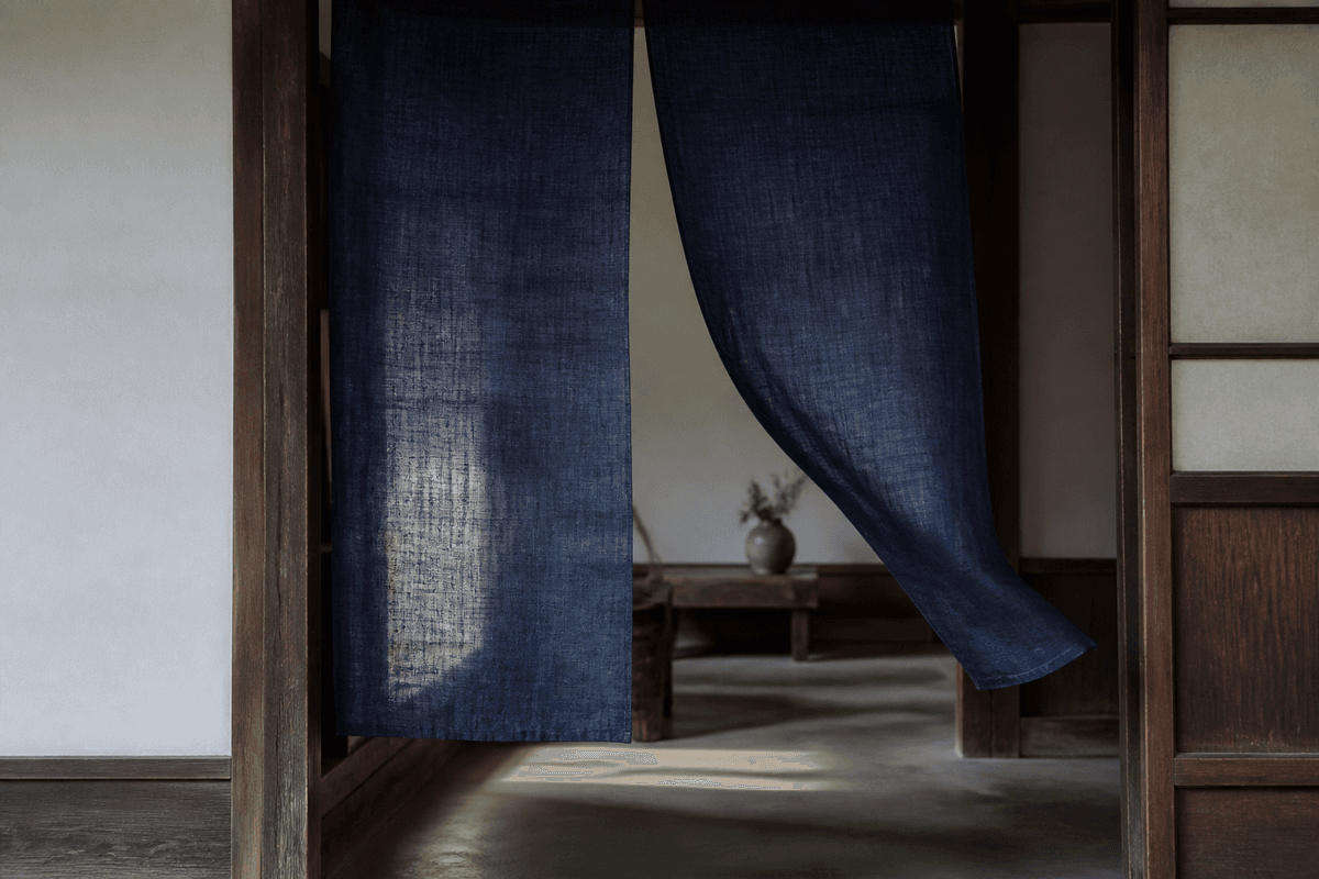 An indigo noren moving gently in a wooden Japanese doorway