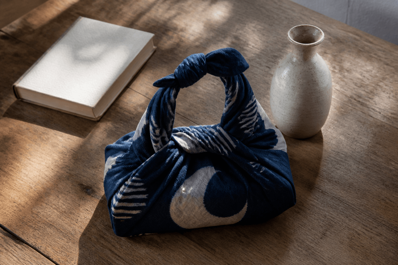 An indigo furoshiki tied around everyday objects on a wooden table